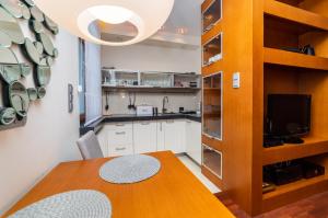 a kitchen with a wooden table and a dining room at Broadway - Neptun Park by OneApartments in Gdańsk