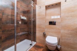 a bathroom with a toilet and a glass shower at Broadway - Neptun Park by OneApartments in Gdańsk