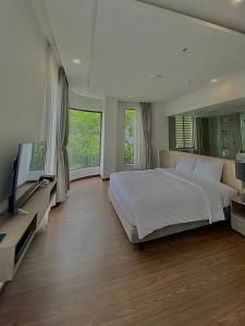 a bedroom with a large bed and a flat screen tv at Mansion Park Hotel & Apartment in Bien Hoa