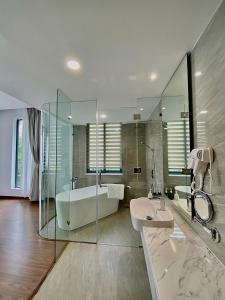 a bathroom with a glass shower and a tub and a sink at Mansion Park Hotel & Apartment in Bien Hoa