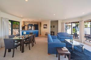 a living room with a blue couch and a table and chairs at On The Rocks in Nelson