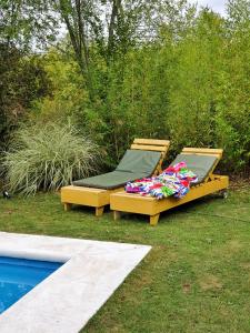 dos camas sentadas en el césped junto a una piscina en Cabaña Josefina en Los Reartes