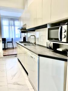 a kitchen with white cabinets and a microwave at City centre HOTEL STYLE APARTMENT in Baku