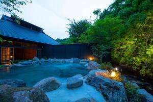 a hot tub in a yard with rocks and a building at Miyama Sansou in Minamioguni