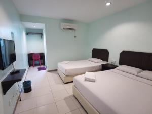 a hotel room with two beds and a flat screen tv at GS BERA HOTEL SDN BHD in Kampong Kerayong
