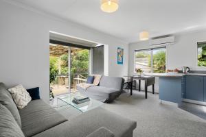 a living room with a couch and a table at The Wee Blue Bach - Waikanae Beach Holiday Home in Waikanae +12 photos