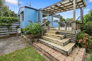 a home with a wooden staircase leading to a blue house at The Wee Blue Bach - Waikanae Beach Holiday Home in Waikanae
