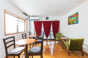 una habitación con mesas y sillas y una cortina roja en Bigtree Guesthouse en Izumi-Sano