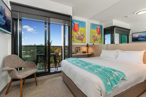 a bedroom with a bed and a chair and a window at Mercure Bendigo Schaller in Bendigo