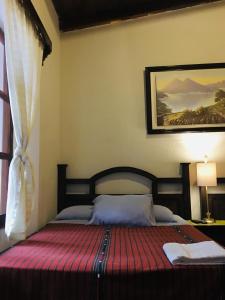 a bedroom with a bed with a red blanket at Dionisio Inn in Antigua Guatemala