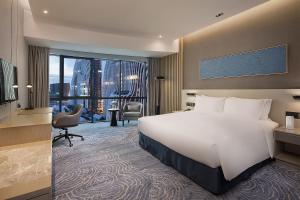 南京市にあるHoliday Inn - Nanjing South Station, an IHG Hotelのベッドと大きな窓が備わるホテルルームです。