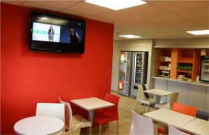 Habitación con mesas y TV en la pared. en Première Classe Perpignan Nord - Aéroport, en Rivesaltes