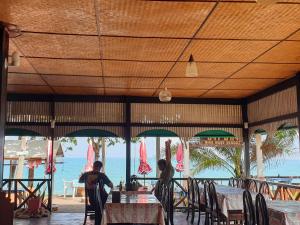 two people sitting at tables in a restaurant with the ocean at Mira Mare Resort Koh Samui in Lamai