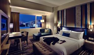 a hotel room with a bed and a desk and a room at Mercure Serpong Alam Sutera in Serpong
