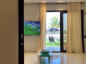 a living room with a tv on a wall with a soccer game at Mokango Apartment Hawana Salalah in Salalah