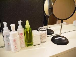a bathroom counter with bottles of soap and a mirror at First Cabin Kansai Airport in Izumi-Sano