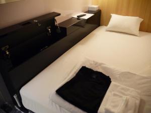 a white bed with a black bag sitting on it at First Cabin Kansai Airport in Izumi-Sano