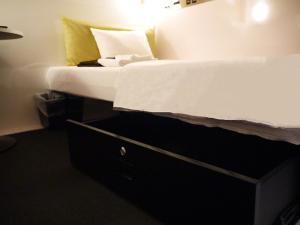 a bedroom with a bed with a black drawer at First Cabin Kansai Airport in Izumi-Sano