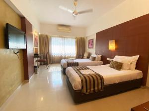 a hotel room with two beds and a flat screen tv at Hotel Park Plaza in Panaji +33 photos
