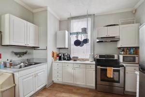 a kitchen with white cabinets and a sink and a stove at Bywater Home, Parking and Pet Friendly Retreat in New Orleans
