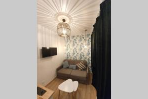 Una sala de estar con un sofá y una lámpara de araña. en Home Sweet Home Pigalle Montmartre Jungle, en París