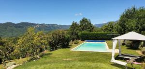 una piscina en un patio con sombrilla y sillas en La Grange - Chez Gisi - für Naturliebhaber, Abenteurer und Geniesser, en Rocles