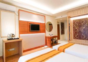 ein Hotelzimmer mit 2 Betten und einem Flachbild-TV in der Unterkunft Khas Parapat in Parapat