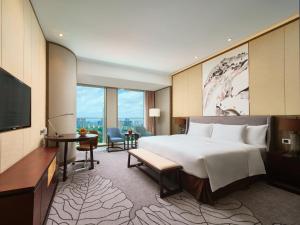 Crowne Plaza Nanning City Center, an IHG Hotel في نانينغ: غرفة فندقية بسرير كبير وتلفزيون بشاشة مسطحة