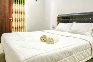 ein weißes Bett mit zwei gewalzten Handtüchern darauf in der Unterkunft Rudi Rooms near Stasiun Cikarang Mitra RedDoorz in Jakarta