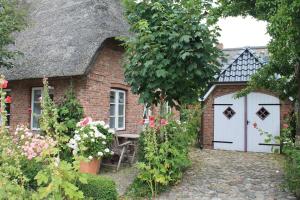 uma pequena casa de tijolos com uma porta branca e um portão em Ferienwohnung Oldsum em Oldsum