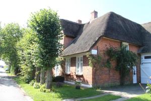 a red brick house with a thatched roof at Kapitän Hansen Haus- Obergeschoss in Oldsum