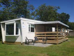 una casita blanca con porche y 2 sillas en Northseachalets Ameland en Buren