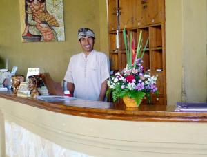 a man standing behind a counter with flowers at Santai Hotel in Amed +37 photos