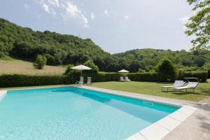 a swimming pool with two chairs and an umbrella at Agriturismo L'Esinante in Cupramontana