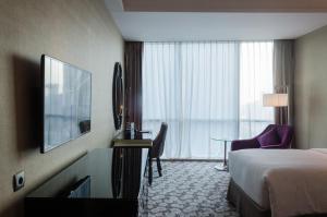ein Hotelzimmer mit einem Bett und einem Schreibtisch mit einem TV in der Unterkunft Hotel Ciputra World Surabaya managed by Swiss-Belhotel International in Surabaya