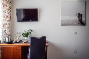 a desk with a chair and a television on a wall at Garni Hotel & Appartements Nordstrand in Nordstrand