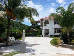 a white house with a patio and trees at Zanboza Guesthouse in La Digue