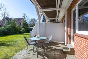 a patio with a table and chairs and a fence at App-1-Alkersum in St. Peter-Ording