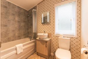 a bathroom with a sink and a tub and a toilet at Hemingway Lodge with Hot Tub in York +11 photos