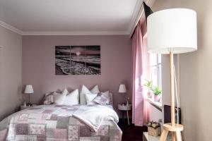 
a bedroom with a bed, a lamp and a painting on the wall at Garni Hotel & Appartements Nordstrand in Nordstrand
