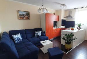 ein Wohnzimmer mit einem blauen Sofa und einer Küche in der Unterkunft Apartments TB in Porat