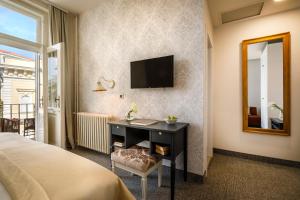 a bedroom with a desk and a television on a wall at Hotel Lungomare Opatija - Liburnia in Opatija