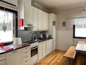 uma cozinha com armários brancos, um lavatório e uma janela em Villa Taikinajoki em Pertunmaa