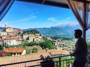 Un uomo in piedi su un balcone che guarda una città di Hotel Ristorante El Caracol a Mulazzo