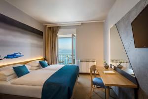 a hotel room with a bed and a desk with a view at Hotel Istra - Liburnia in Opatija