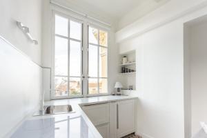 une cuisine blanche avec un évier et une fenêtre dans l'établissement Seaside Studio by iCasamia, à Nice