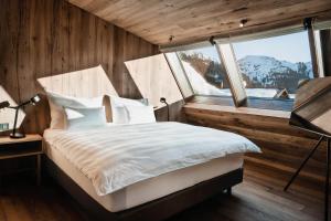 a bedroom with a bed and a large window at Berghotel Biberkopf in Warth am Arlberg