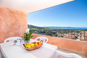 a basket of fruit on a white table with a view at Residence Pala Stiddata with panoramic swimming pool in Trinità d'Agultu e Vignola
