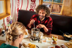 a man and a woman sitting at a table eating food at Alpine Hotel by SnowWorld in Landgraaf