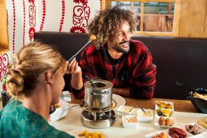 a man and a woman sitting at a table with food at Alpine Hotel by SnowWorld in Landgraaf
